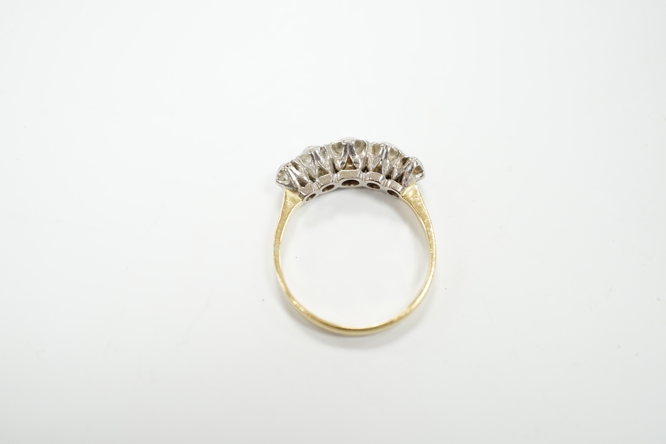 An antique yellow metal and graduated old round cut diamond set half hoop ring, size Q, gross weight 4 grams.